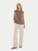 Woman wearing a brown sleeveless top and beige pants on a white background. #color_taupe