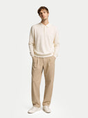 Man wearing a white sweater and beige pants on a white background #color_cream-white
