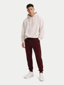A pair of dark burgundy cashmere jogger sweatpants with an elastic waistband, drawstring, and side pockets, shown flat against a light gray background. #color_dusty-plum
