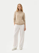 A light beige knit zip-up cashmere jacket with a mock neck, ribbed cuffs, and side pockets, displayed against a light gray background. #color_dusty-beige