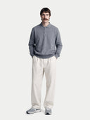 Man wearing a gray cashmere sweater and white pants on a white background.  #color_gray