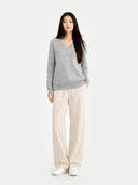 Woman wearing a gray sweater and beige pants on a white background. #color_stone-silver