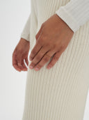 A woman modeling a matching off-white long-sleeve top and wide-leg cropped pants, paired with black slide sandals, against a plain white background. #color_white