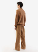 A man standing wearing a beige cashmere polo sweater with a round neckline and long sleeves. #color_light-brown