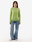 Person wearing a green sweater and blue jeans on a white background. #color_jade-green