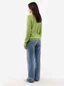 Person wearing a green sweater and blue jeans on a white background. #color_jade-green