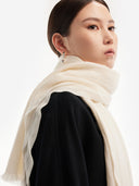 Model wearing white women's cashmere scarf wrapped at the neck, side view with black coat