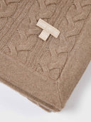 Taupe cashmere cable knit blanket folded, close view of corner with woven label