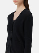 A woman wearing a black lightweight cashmere cardigan with long sleeves and a V-neck collar, paired with a dark skirt.
#color_black