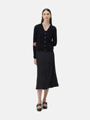 A woman wearing a black lightweight cashmere cardigan with long sleeves and a V-neck collar, paired with a dark skirt.
#color_black
