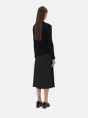 A woman wearing a black lightweight cashmere cardigan with long sleeves and a V-neck collar, paired with a dark skirt.
#color_black